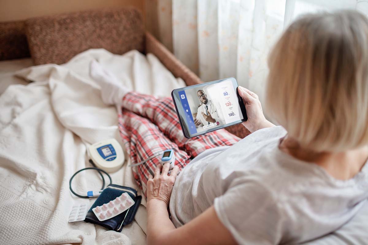 Patient sitting in bed taking vitals remotely to send to their healthcare professional